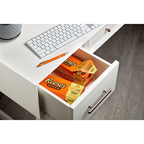 A pack of Reese's Peanut Butter Cups is shown inside an open desk drawer next to a keyboard and pencil, suggesting a quick snack option.