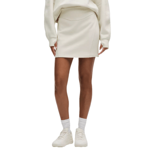 The lululemon Scuba High-Rise Mini Skirt is a white, high-rise skirt paired with a matching sweater. It features a simple, streamlined design, worn with white sneakers and socks.