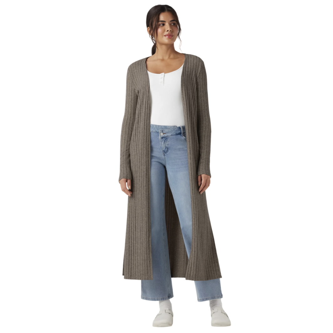 Woman wearing a long, ribbed, brown cardigan over a white top and light blue jeans, paired with white shoes.
