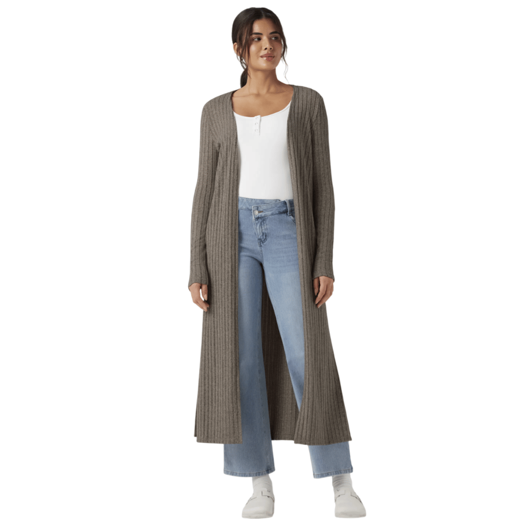 Woman wearing a long, ribbed, brown cardigan over a white top and light blue jeans, paired with white shoes.