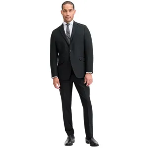 A man is wearing a tailored black suit with a white dress shirt, a patterned tie, and black dress shoes.