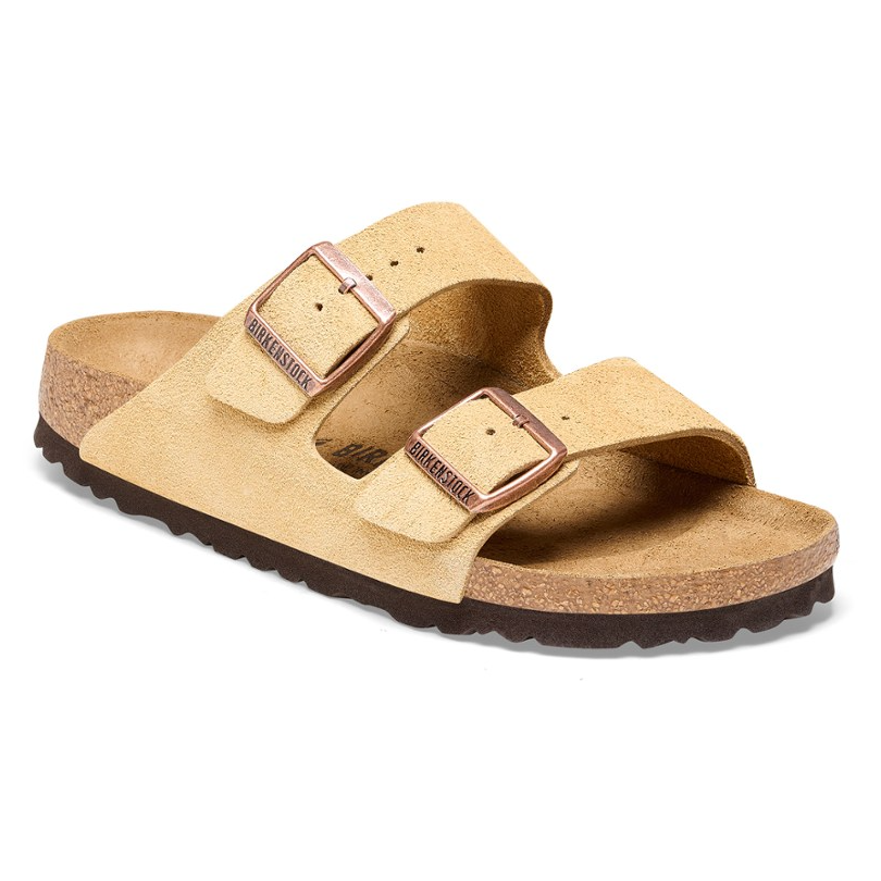 Birkenstock Arizona Sandals feature two beige suede straps with adjustable metal buckles, a cork-latex footbed, and an EVA sole for comfort and support.