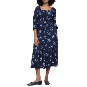 A navy blue midi dress with a floral pattern, featuring a smocked square neckline and three-quarter sleeves. The dress has a tiered skirt and is paired with simple black flats.