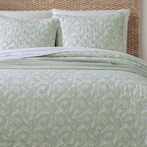 A light green bedding set featuring a quilted pattern with a floral design, complemented by matching pillow shams.