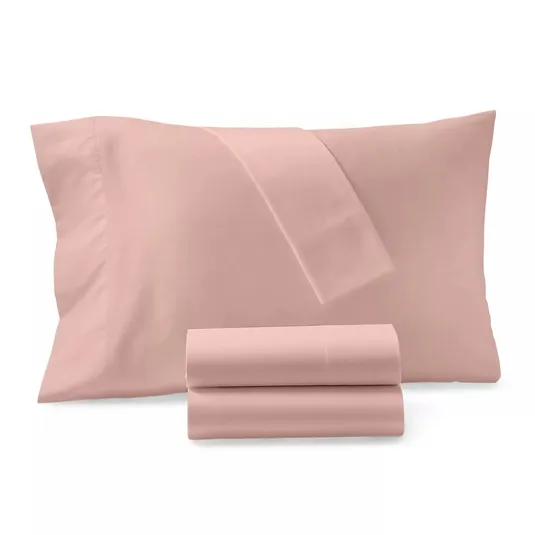 A set of pink bed linens, featuring a folded sheet and pillowcase, with additional sheets rolled in front.
