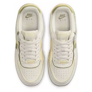 A pair of white Nike Air Force 1 sneakers with yellow accents, viewed from the top.