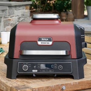 Ninja Woodfire outdoor electric grill with a woodfire flavor feature, digital controls, and a red and black design.