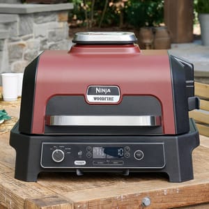 Ninja Woodfire outdoor electric grill with a woodfire flavor feature, digital controls, and a red and black design.