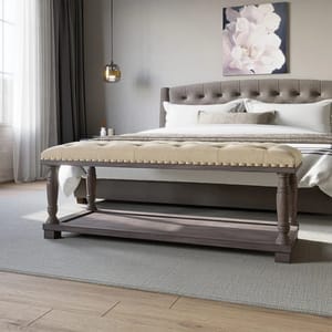 A tufted upholstered bench with wooden legs and a shelf, beside a bed with a tufted headboard.