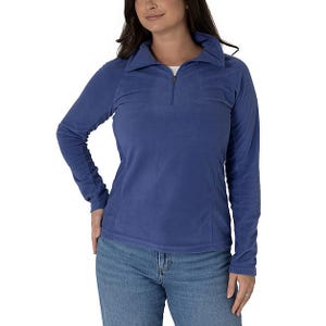 A woman wears a blue Columbia Glacial IV Half Zip Fleece with long sleeves and a stand-up collar, paired with blue jeans.