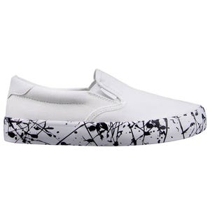 White slip-on sneaker with a black splatter design on the sole.