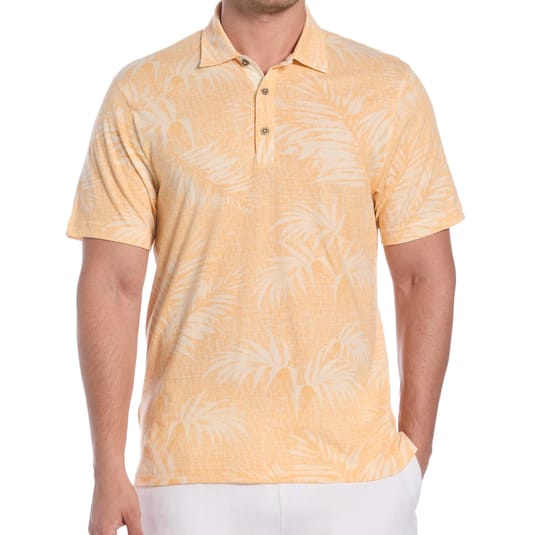 A man is wearing a light orange polo shirt with a subtle palm leaf pattern, paired with white pants.