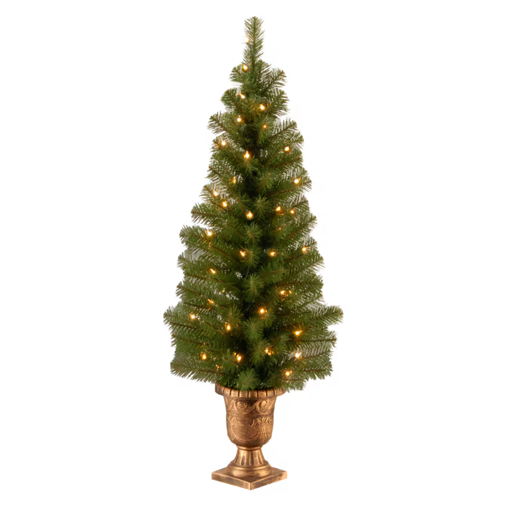 A small artificial Christmas tree featuring warm white lights, set in an ornate, gold-colored urn-style pot.