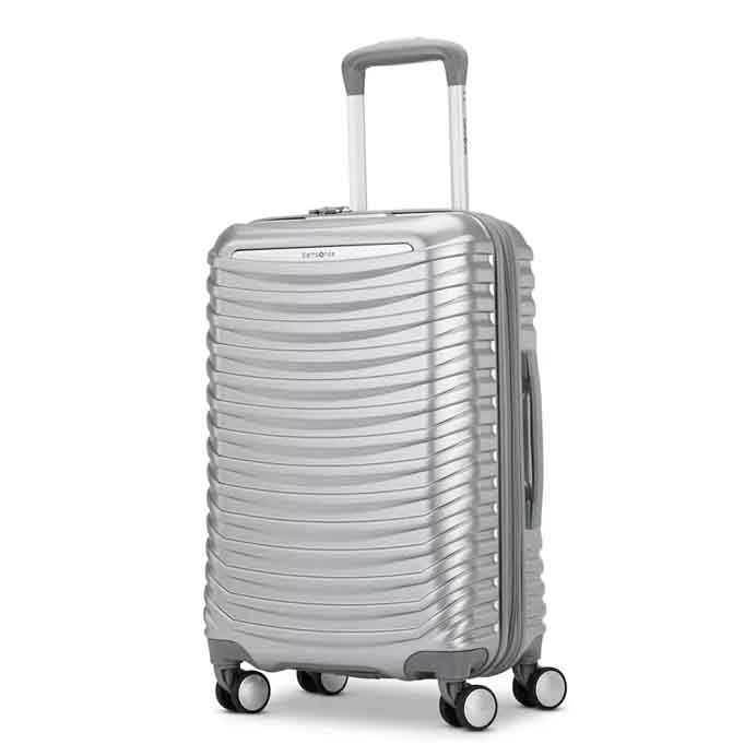 Silver Samsonite carry-on spinner featuring a textured, ribbed design with four multidirectional wheels, a telescopic handle, and a side handle for easy transport.