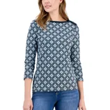 Woman wearing a diamond-patterned, long-sleeve top with a round neckline, paired with blue jeans.