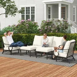 Outdoor patio seating set with metal frames and white cushions, featuring a loveseat, two armchairs, a coffee table, and an ottoman on a deck with floral and leafy surroundings.