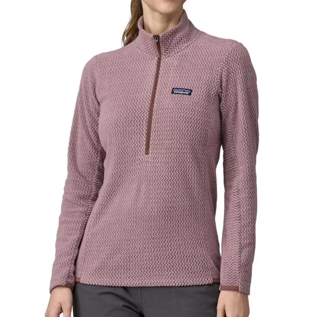 The Patagonia R1 Air Pullover is a women’s long-sleeve, half-zip fleece in a light purple color with a textured pattern. It features a stand-up collar and the Patagonia logo on the chest.