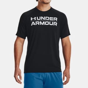 A man wearing a black Under Armour T-shirt with white lettering and blue shorts.