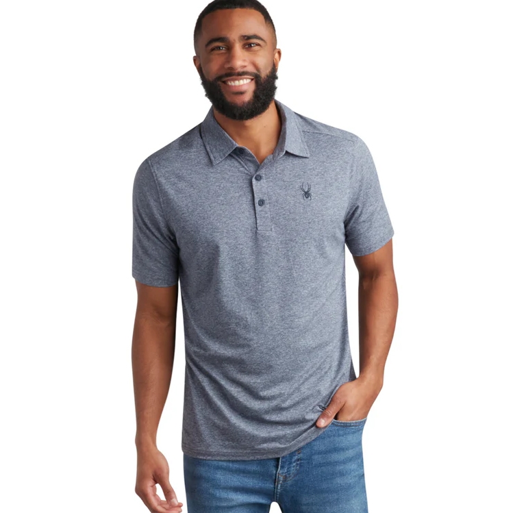 A man is wearing a casual gray polo shirt with a small black emblem on the chest, paired with blue jeans.