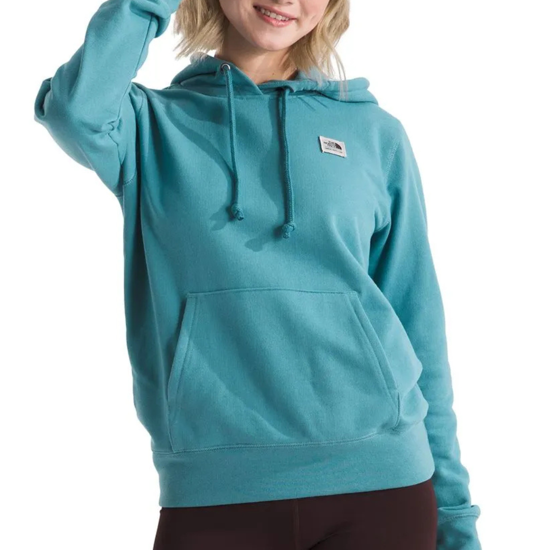 A person is wearing a teal hoodie with a front pocket and drawstrings, featuring a small rectangular logo on the chest.