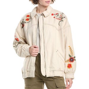 A cream-colored jacket with floral embroidery on the shoulders and sleeves, paired with olive green cargo pants.