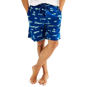 Blue shorts with a tropical palm tree print, featuring an elastic waistband and drawstrings, worn by a person standing barefoot.