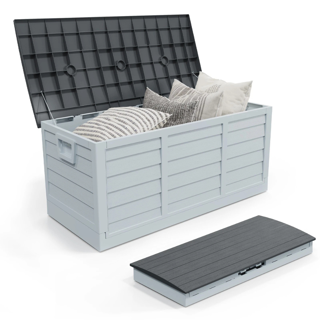 A gray outdoor storage box with a black lid is shown open, containing decorative cushions. A separate folded version of the lid is displayed in front.