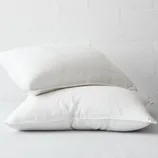Two white cooling gel pillows with subtle stripes, stacked against a light-colored textured wall.