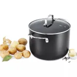 A black cooking pot with a glass lid is shown alongside unpeeled potatoes, potato peel, butter, black peppercorns, and a bay leaf.