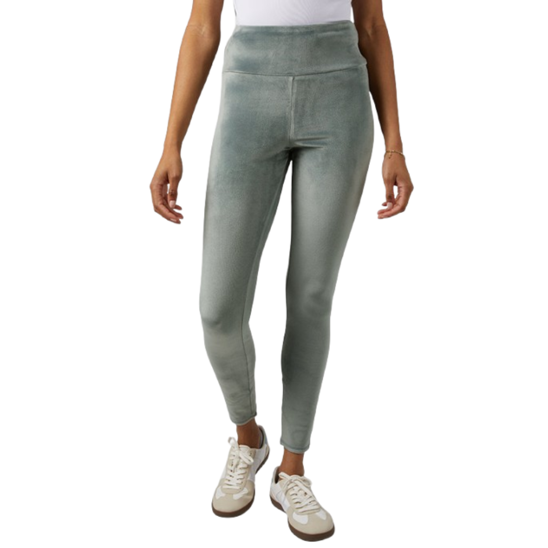 A person is wearing high-waisted, light green velvet leggings paired with white sneakers.