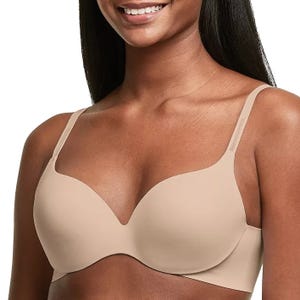 A woman is wearing a beige underwire bra with smooth, molded cups and adjustable straps.
