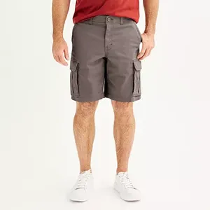 A man is wearing gray cargo shorts that reach above the knee, with multiple pockets on the sides, a button closure, and white sneakers.