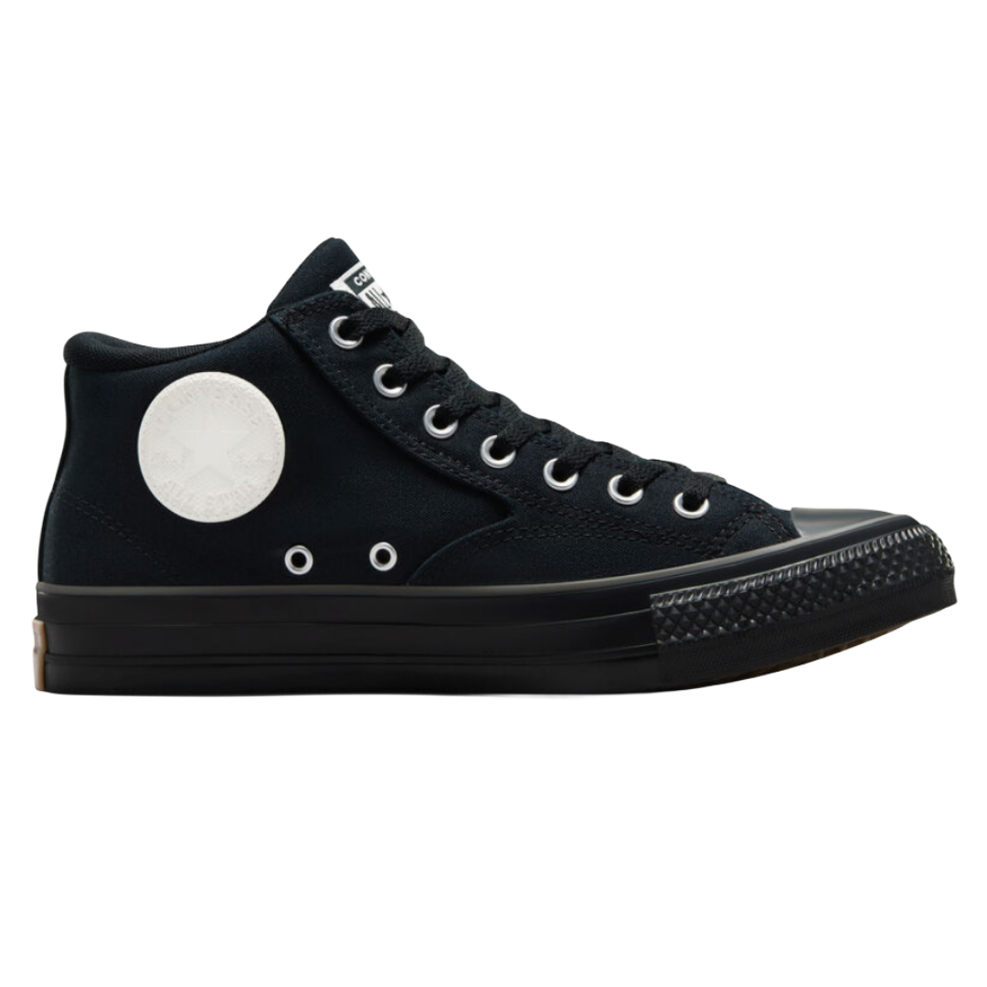 Black high-top sneaker with white circular logo, featuring metal eyelets and black rubber toe cap and sole.