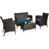 4-piece patio furniture set with a glass-top coffee table, two armchairs, and a loveseat, all with brown wicker frames and blue cushions. Includes three cups, saucers, and a potted plant on the table.
