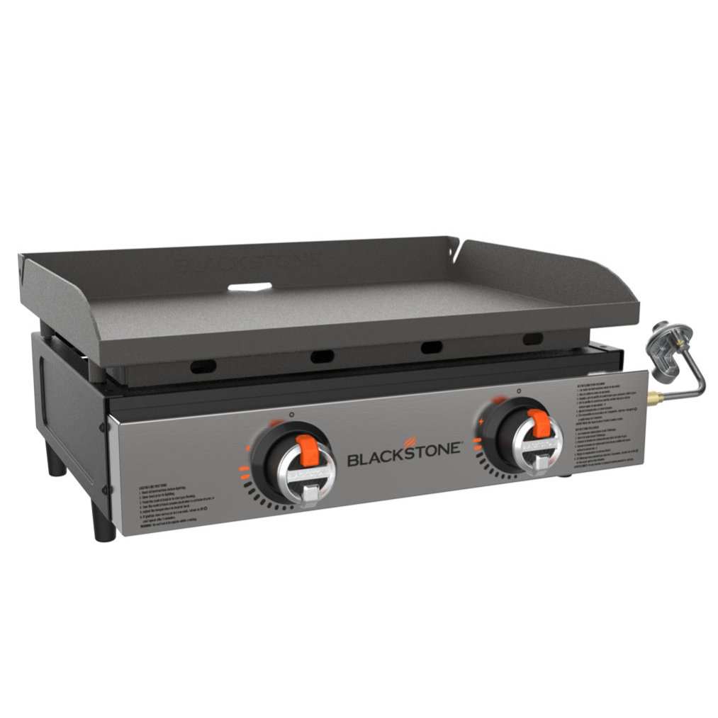 Two-burner Blackstone tabletop gas griddle featuring a flat cooking surface with side shields, ignition knobs, and a propane connection on the side.