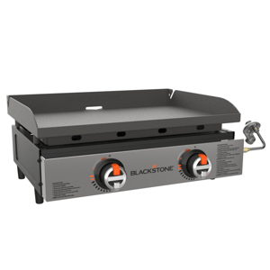 Two-burner Blackstone tabletop gas griddle featuring a flat cooking surface with side shields, ignition knobs, and a propane connection on the side.