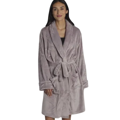 A woman is wearing a soft, plush robe tied at the waist with long sleeves and a shawl collar in a bedroom setting.