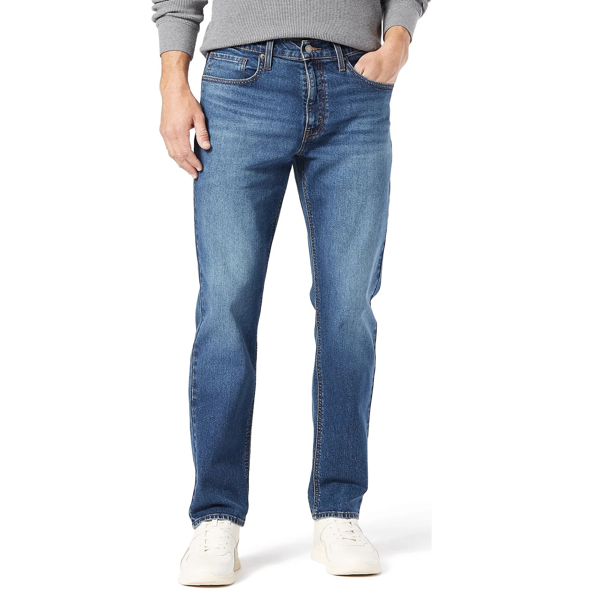 Levi Strauss Signature Jeans are classic blue denim, straight-leg style with a medium wash and five-pocket design. They are worn with a gray sweater and white sneakers.
