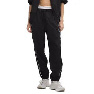 A person is wearing black athletic jogger pants with white stripes along the sides, paired with a white waistband and light-colored sneakers.