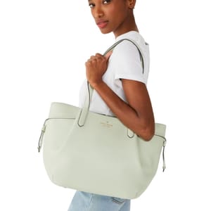 A woman is carrying a pastel green tote bag on her shoulder.