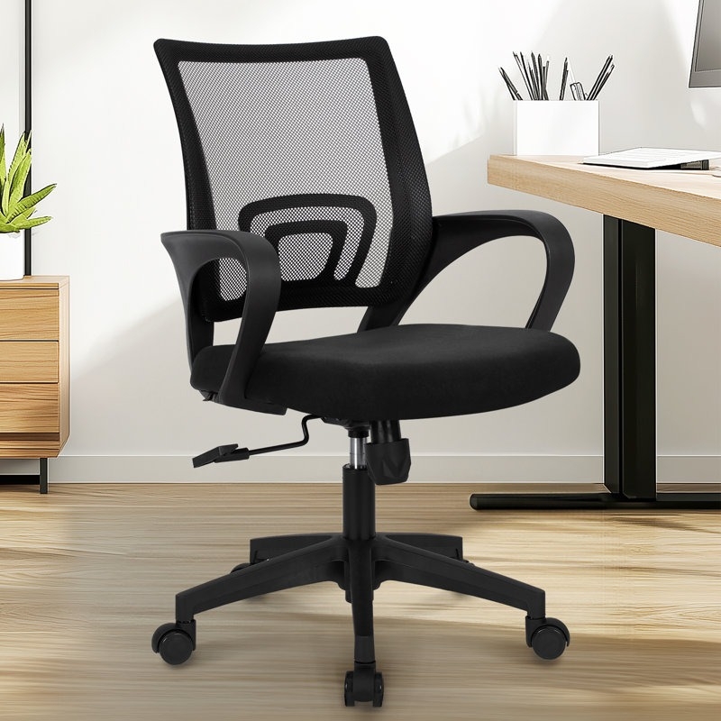 Black mesh office chair with curved armrests, adjustable height, and a five-wheel base, placed in a modern office setting with a desk and minimal decor.