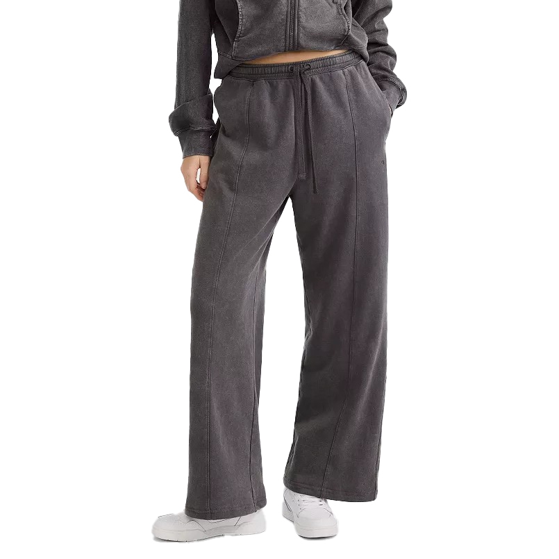 A person is wearing a dark gray drawstring sweatpants and matching zip-up hoodie, paired with white sneakers. The outfit has a comfortable, casual style with wide-leg pants and side pockets.
