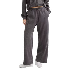 A person is wearing a dark gray drawstring sweatpants and matching zip-up hoodie, paired with white sneakers. The outfit has a comfortable, casual style with wide-leg pants and side pockets.