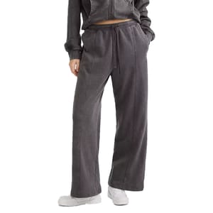 A person is wearing a dark gray drawstring sweatpants and matching zip-up hoodie, paired with white sneakers. The outfit has a comfortable, casual style with wide-leg pants and side pockets.