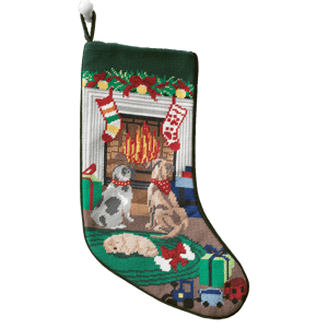 A festive needlepoint stocking featuring three dogs near a fireplace, adorned with holiday decorations. Two stockings hang above the fire, surrounded by wrapped gifts and toys. The design is colorful and detailed, capturing a cozy holiday scene.