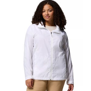 A woman wearing a white zip-up jacket with a stand-up collar, along with tan pants.