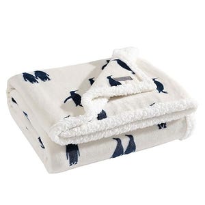 A cream-colored Eddie Bauer throw blanket with a Sherpa lining and a pattern of navy blue fish.