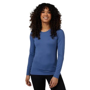 A woman is wearing a blue, long-sleeve, fitted 32 Degrees Air Mesh Tee with a crew neck and black pants. The shirt is designed for comfort and breathability.