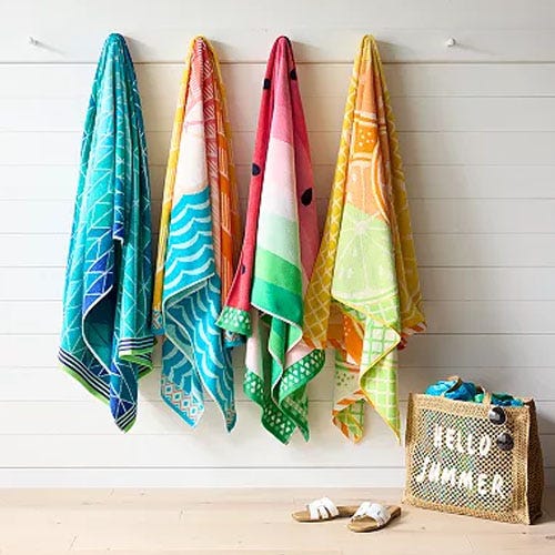 four beach towels hanging on a white wall