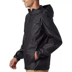 A man wearing a black hooded rain jacket with a logo on the chest, paired with khaki pants.